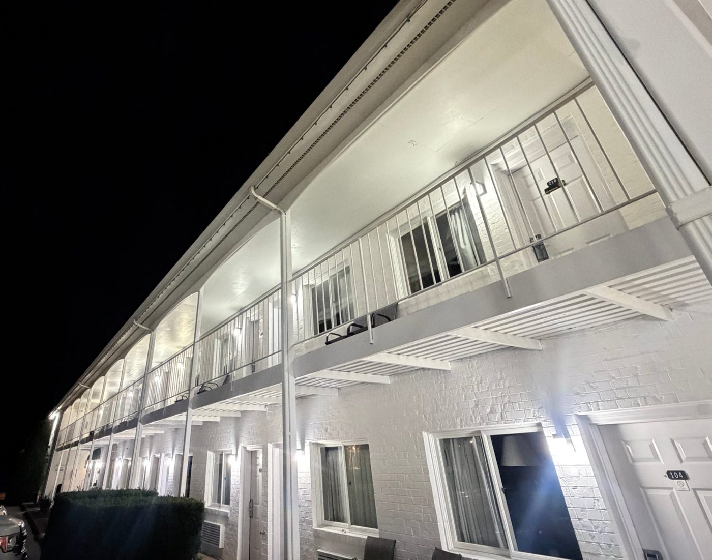 Same inn after renovation, brick limewashed bright white with new lighting, lit up at night