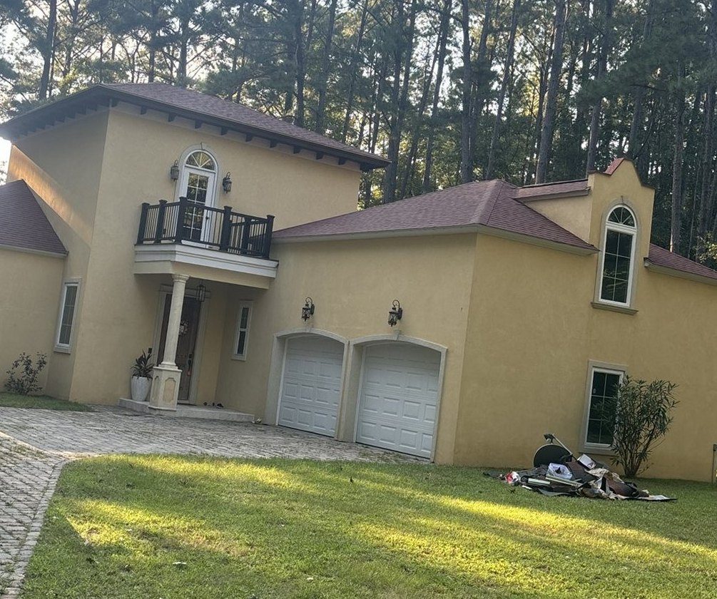 Same stucco home with the tree removed and the garage roof repaired